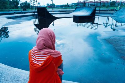 Rear view of woman looking at wet skateboard park during sunset