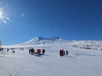 People on snowcapped mountain against clear sky