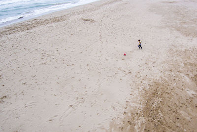 High angle view of boy playing soccer on sand at beach