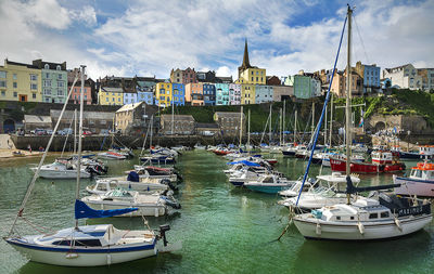 Boats moored in river with city in background