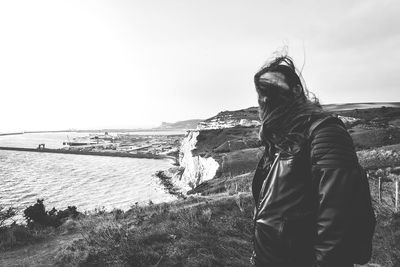 Rear view of man looking at sea shore against sky