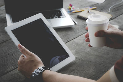 Midsection of man holding coffee cup on table