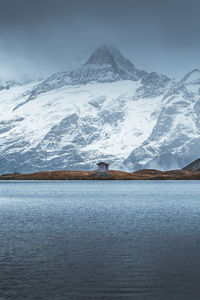 Awesome moody view of a small hut near bachalpsee lake with beautiful snow covered swiss mountains