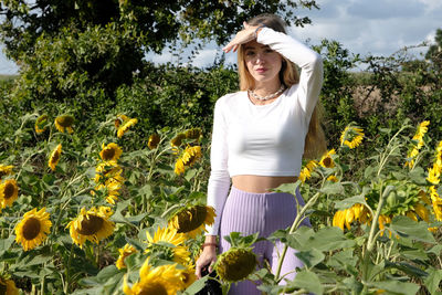 Beautiful woman standing by plants against trees