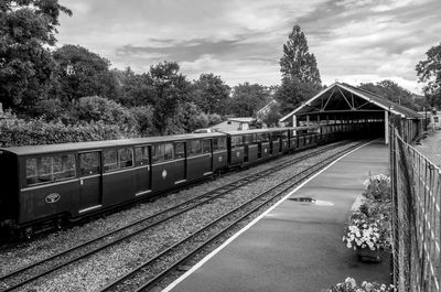 View of trains at railroad station against cloudy sky