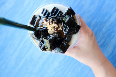 Close-up of hand holding ice cream against blue sky