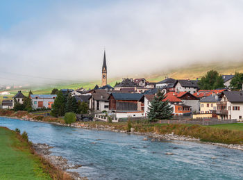 Buildings by river against sky