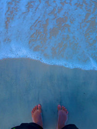 Low section of person standing at beach