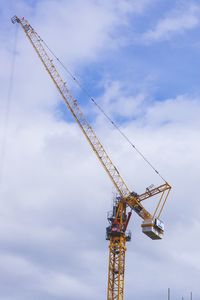 Low angle view of cranes at construction site against sky