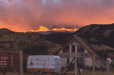 Houses by mountains against sky during sunset