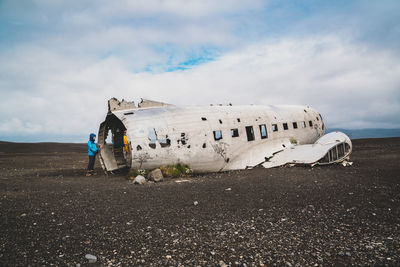 Damaged airplane on airport runway against sky