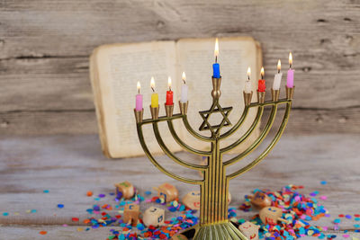 High angle close-up of lit colorful candles with confetti on wooden table