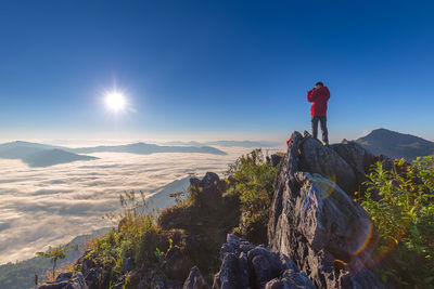 Man on rock by mountains against sky