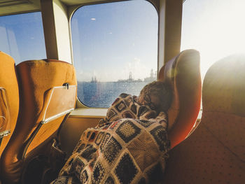 Woman napping on vehicle seat by window