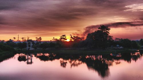 Scenic view of lake against cloudy sky at sunset