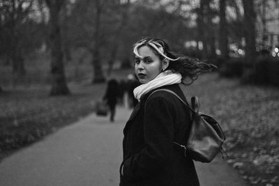 Side view portrait of woman with tousled hair standing at park