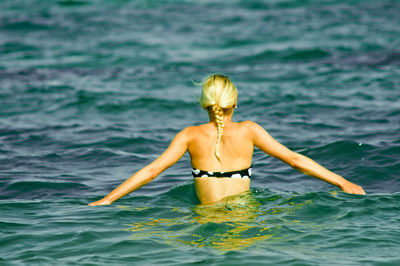 Rear view of woman wearing bikini in sea