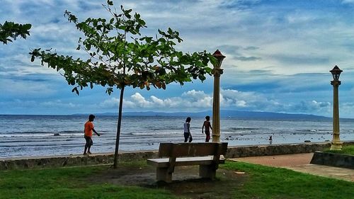 Men sitting at beach against sky