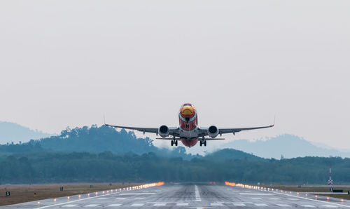 Airplane flying on runway against sky