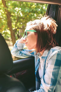 Young woman looking through window while traveling in car