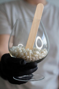 Close up view. a young woman holding in hands a glass with white wax granules