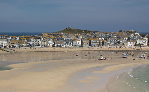 People on beach against sky in city