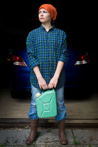 Full length of young woman standing against car at night