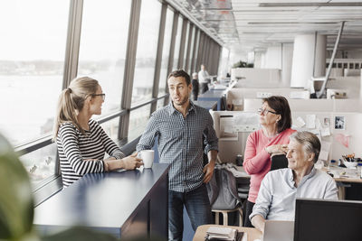 Business people discussing at cubicle in office