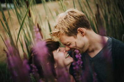 Couple laughing by purple plants on land