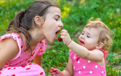 Baby girl feeding berry to sister