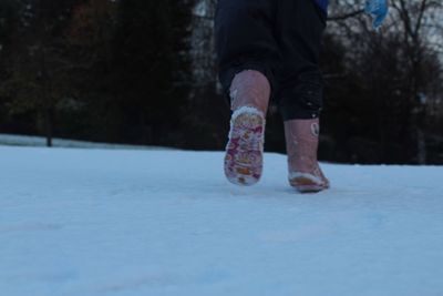 Low section of man standing on snow covered road