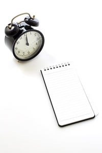 High angle view of clock on book against white background