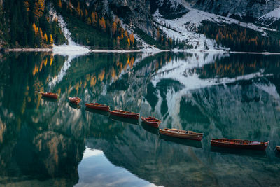 Boats in lake against snowcapped mountains