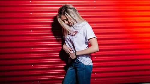 Midsection of woman standing against red wall