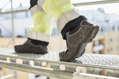 Low section of worker walking on metal platform at construction site