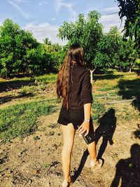 Rear view of woman with umbrella against trees