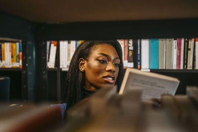 Young woman searching book in library at university