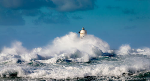 The lighthouse of the mangiabarche shrouded by the waves of a mistral wind storm
