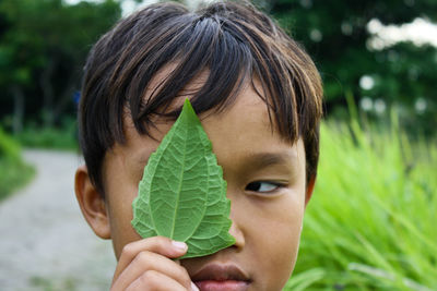 Close-up portrait of boy holding leaf