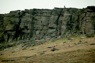 Low angle view of people on rock against sky
