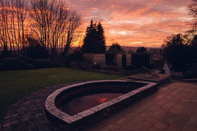 Scenic view of park by buildings against sky during sunset