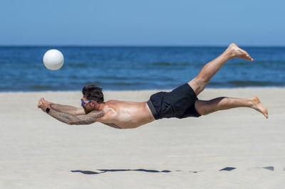 Full length of shirtless man on beach against sky
