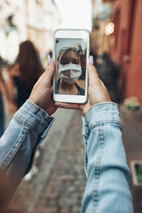 Midsection of man photographing with mobile phone