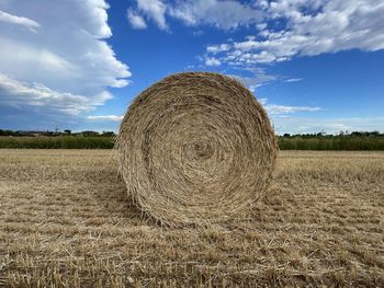 Hay bales on field against sky