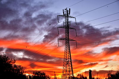 Low angle view of silhouette electricity pylon against dramatic sky