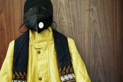 Portrait of person wearing mask against wooden wall