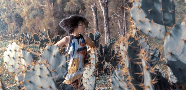 Woman standing by cactus plants in forest