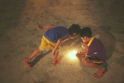 High angle view of boys burning cracker during diwali at night