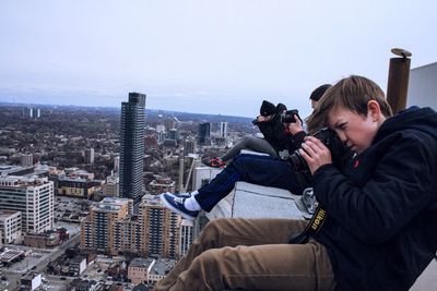 Photographers photographing cityscape while sitting on building terrace