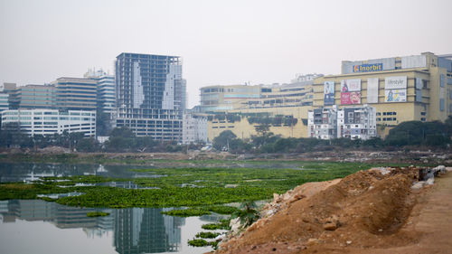 Buildings by river against clear sky